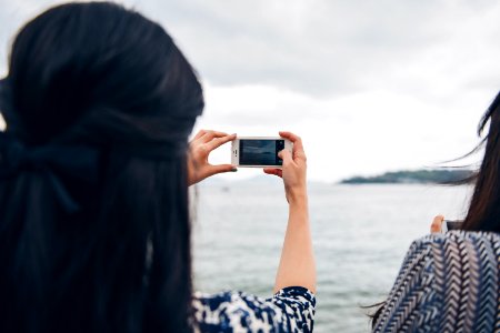woman using smartphone in front of seawater photo