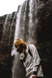 woman in knit cap standing near waterfalls photo