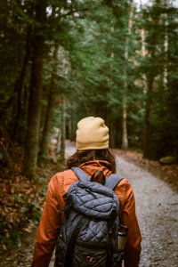 woman carrying backpack walking towards the forest photo