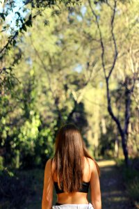 woman wearing black sports bra facing the woods photo