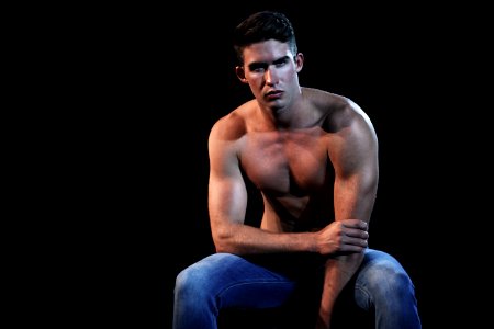 topless man wearing blue denim jeans sitting photo