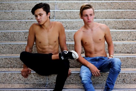 two topless men wearing denim jeans sitting on stairs photo