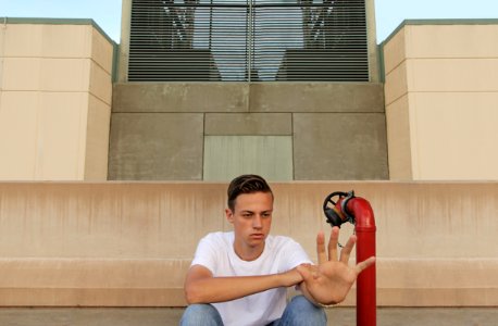 man wearing white t-shirt showing left palm while sitting near building