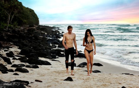 man and woman walking beside body of water