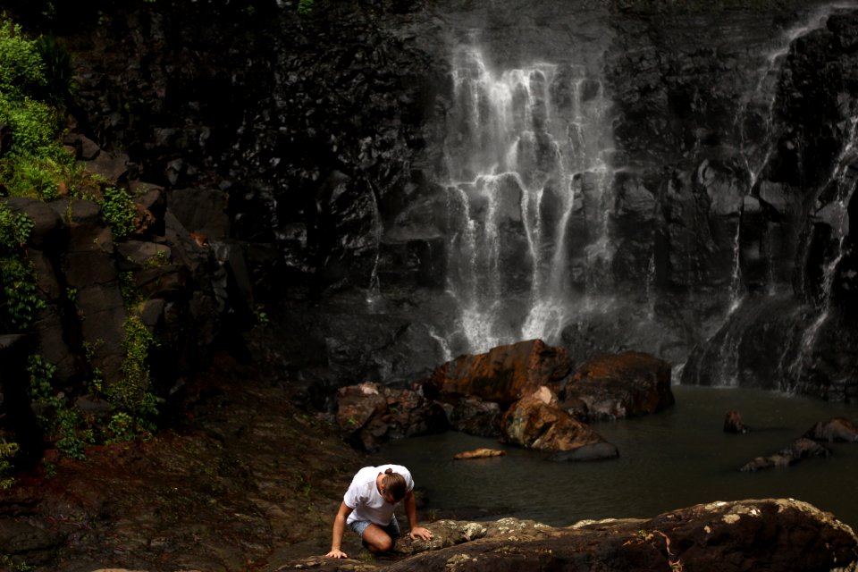 person climbing on rock near water fall photo