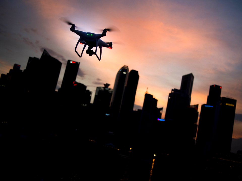 silhouette of quadcopter drone hovering near the city