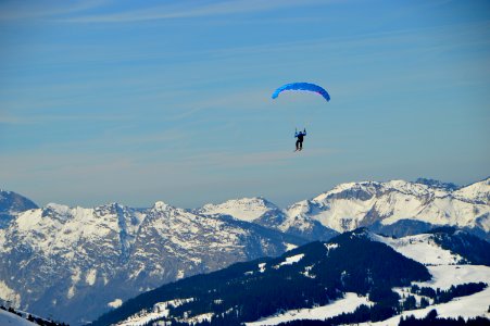 person parachuting above snow covered mountains