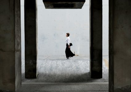 woman walking under a concrete bridge during daytime photo