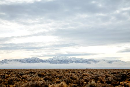 barren field across mountain range photo during cloudy day photo