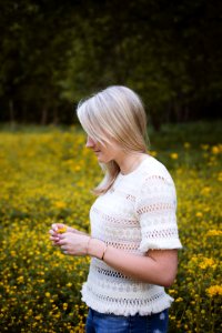 woman wearing white blouse standing and holding yellow flower surrounded with flowers photo