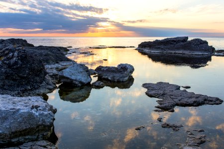 rocks on body of water under cloudy sky photo