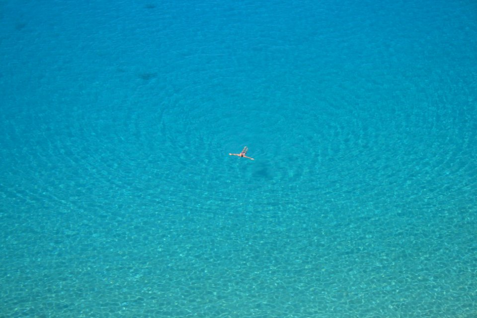 aerial photo of person swimming on body of water during daytime photo