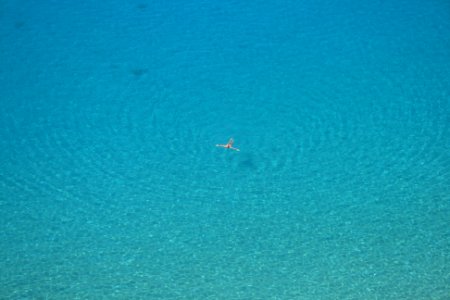 aerial photo of person swimming on body of water during daytime photo