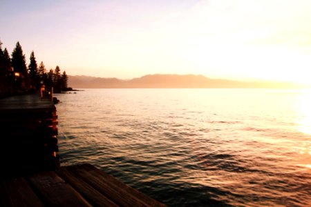 wooden dock on ocean during golden hour photo