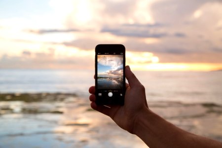 person holding smartphone showing ocean photo