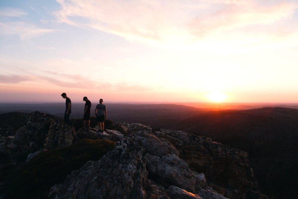 three person standing on mountain during daytime