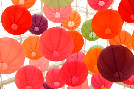 Large round colorful balloons floating to the roof of a glass house.