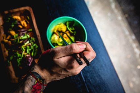 person holding chopsticks near green bowl photo