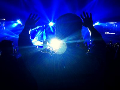 silhouette of a person raising hands towards the stage photo