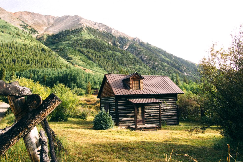 brown wooden house near mountains at daytime photo