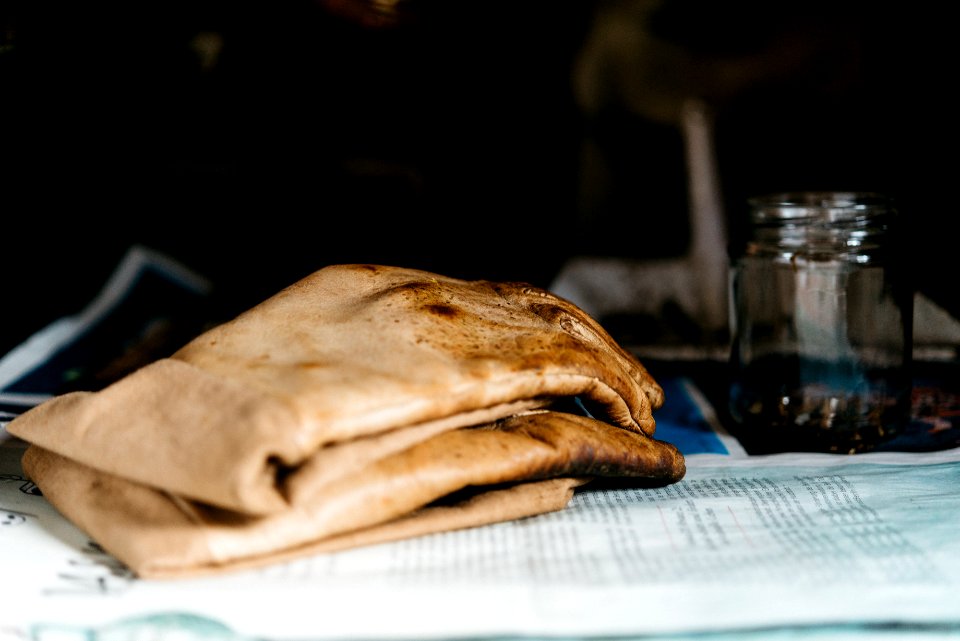 pair of brown leather gloves beside glass jar on newspaper