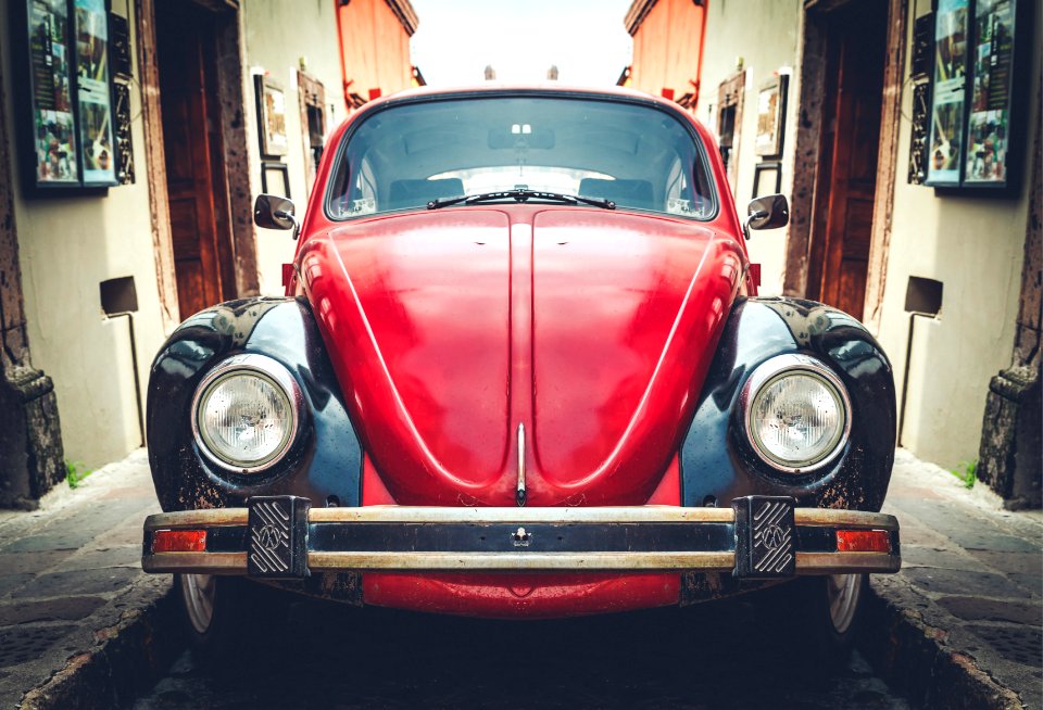 photo of red and black Volkswagen Beetle in alley