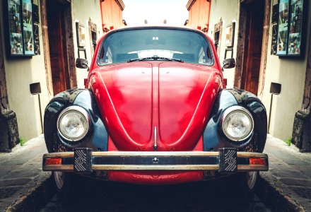 photo of red and black Volkswagen Beetle in alley photo
