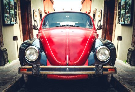 photo of red and black Volkswagen Beetle in alley