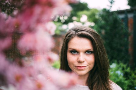 shallow focus photography of woman surrounded by flowers during daytime photo