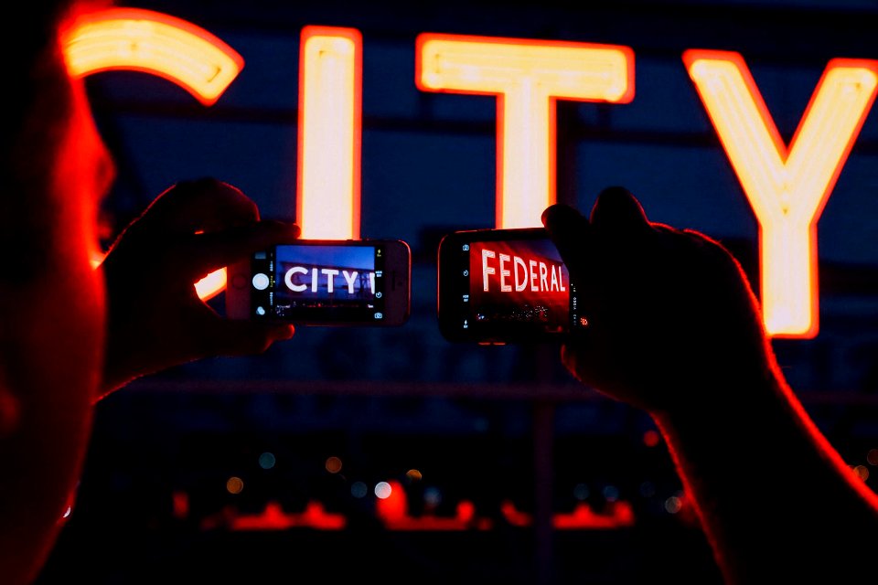 minimalist photography of person taking pictures of City Federal signages