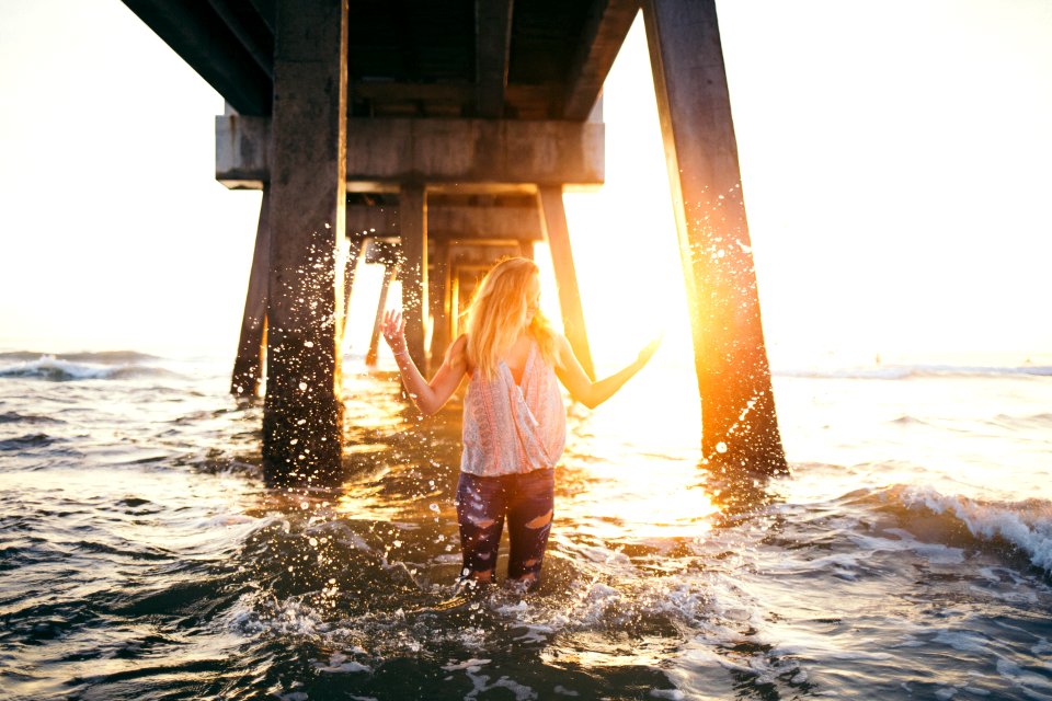 woman stading in water under a dock during golden time