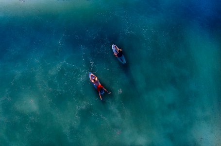 top view photography of two persons on blue surfboard at daytime photo