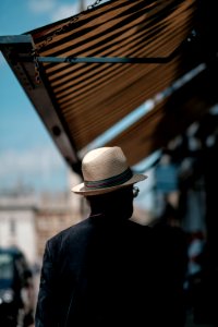 man wearing white straw hat and black shirt walking on the street photo