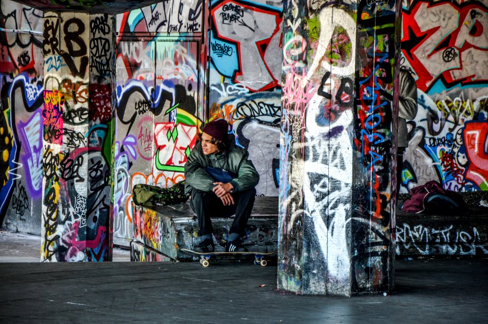 man wearing green jacket sitting with skateboard