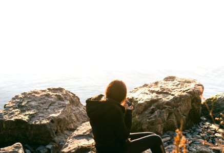 woman wearing black long-sleeved shirt sitting on rock photo