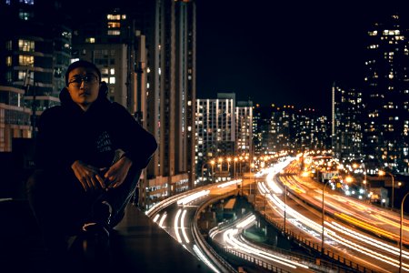 man sitting on rooftop during nighttime in timelapse photo photo