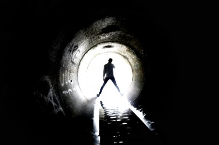 person standing inside sewer tunnel
