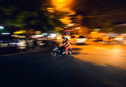 couple riding on black motor scooter during nighttime photo