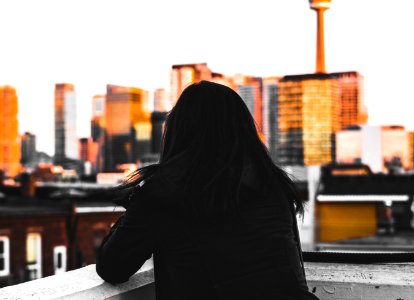 woman leaning on concrete wall looking at city