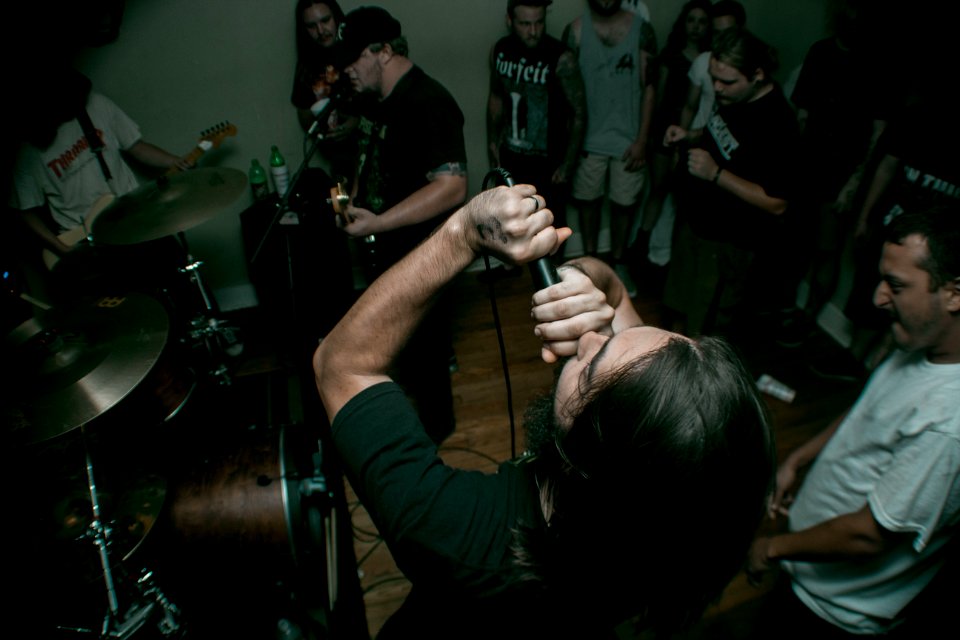 man holding black corded microphone near man wearing white crew-neck t-shirt