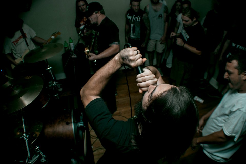 man holding black corded microphone near man wearing white crew-neck t-shirt photo