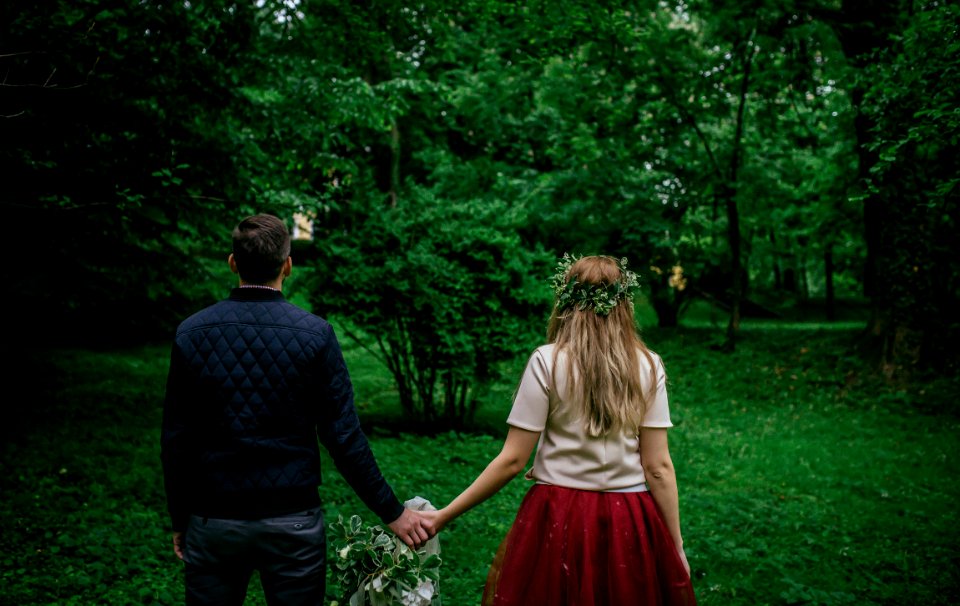 woman and man standing holding hands facing trees