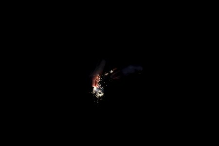 Hands ignite golden sparks using a flint in the dark