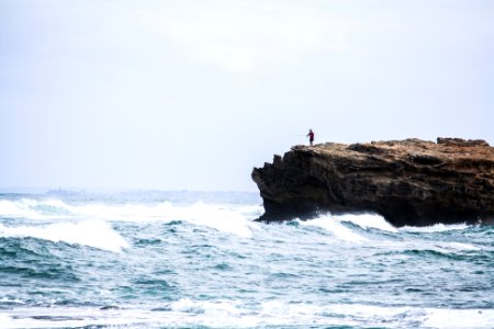 man standing on rock looking at the sea photo