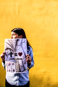 An Indian person holding up a poster that says a cross equals love. photo