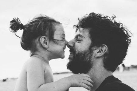 Father and daughter touch noses, smiling in black and white photo photo