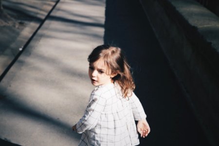 toddler girl walking on gray concrete road at daytime photo