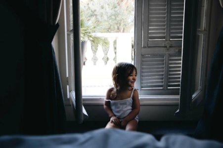 girl sitting by the window during daytime