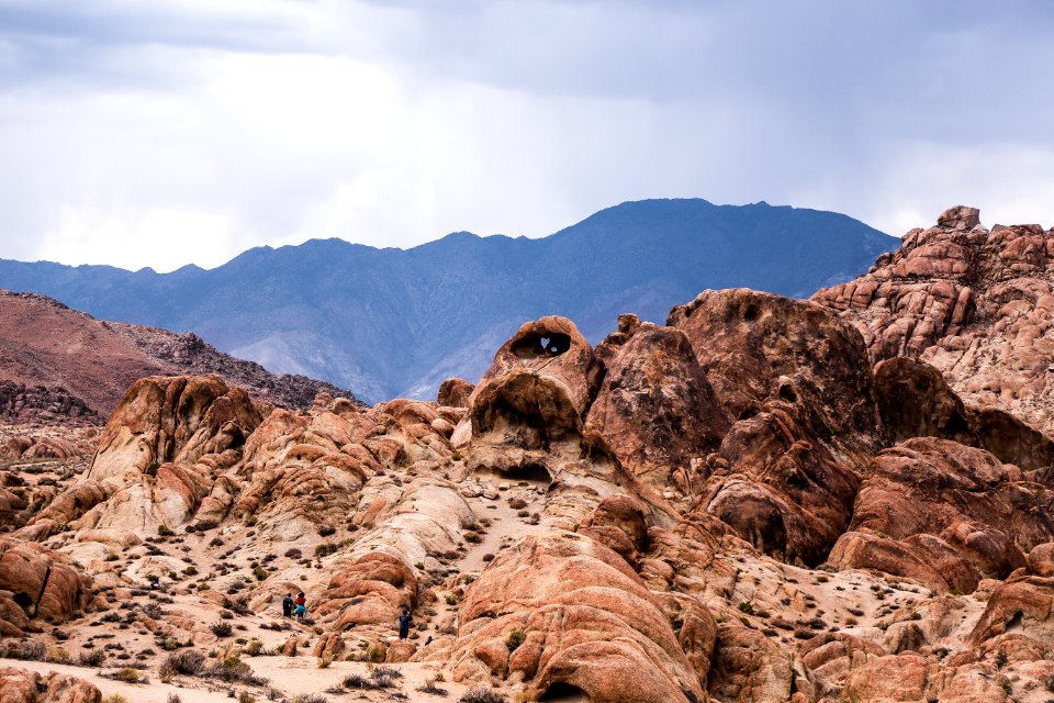 brown rock formation near mountain under cloudy sky