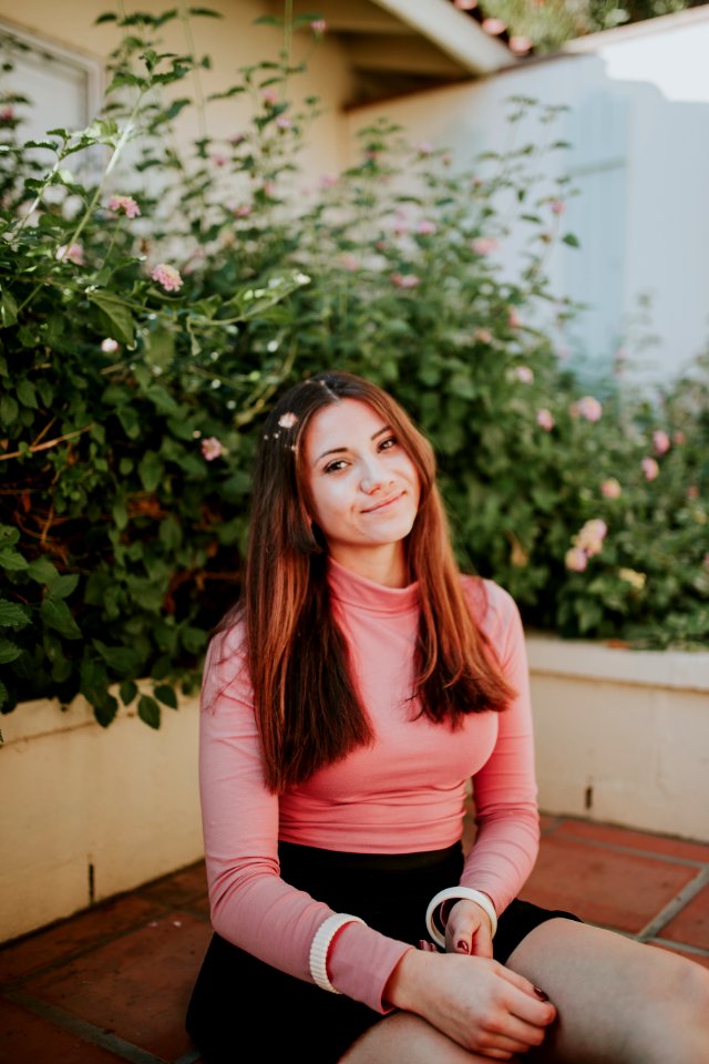 woman sitting near pink flowers at daytime